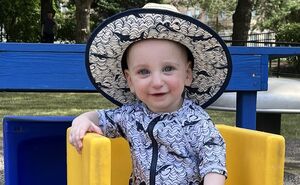 Akiva smiles for the camera while wearing a sun hat and a matching bathing suit.