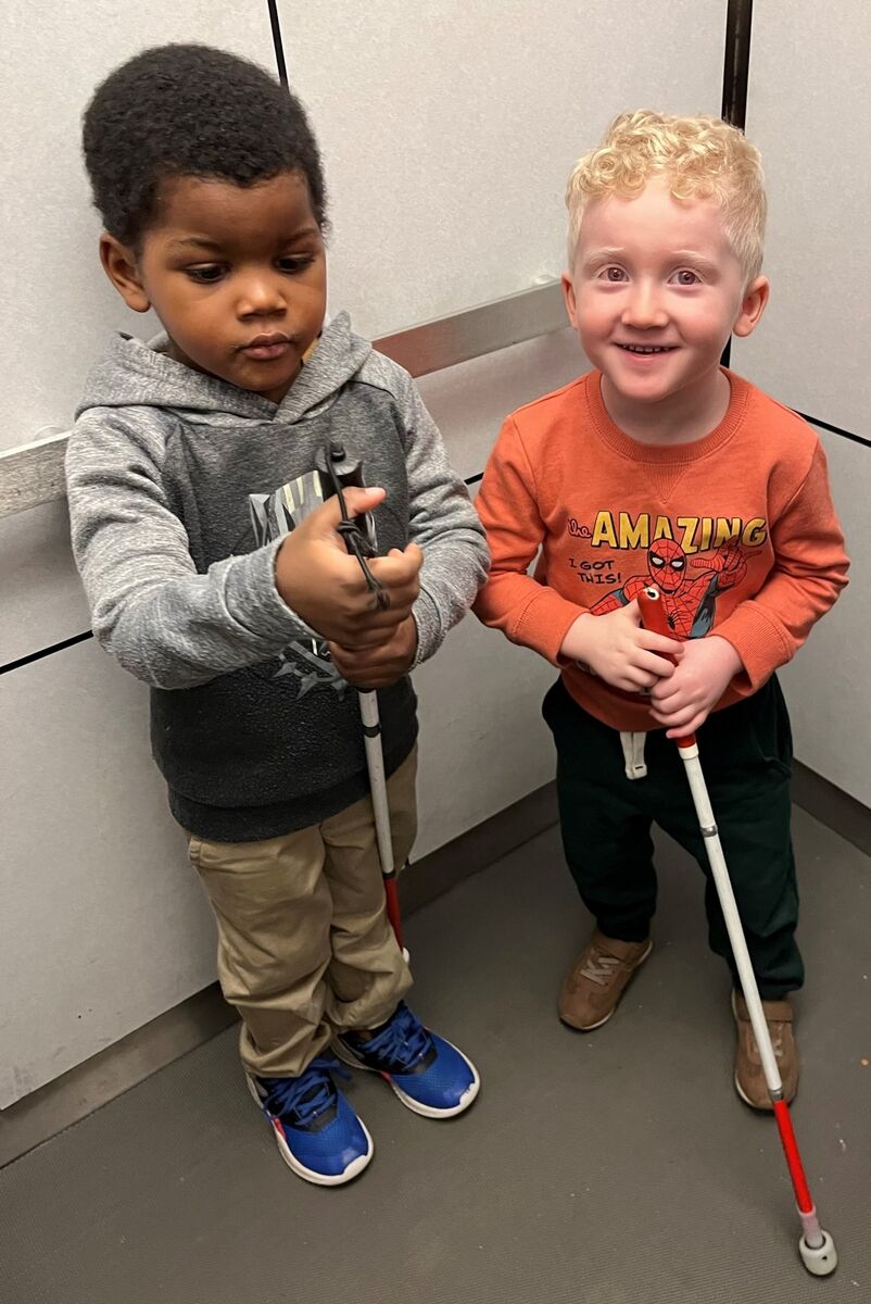 Two preschoolers hold their white canes and are ready for their orientation and mobility lesson.