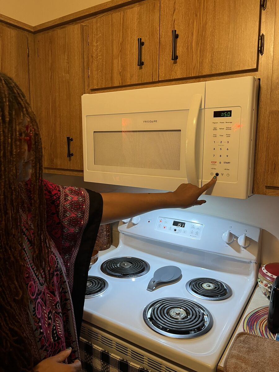 Rosie pushes a button on her microwave with a bump dot on it.