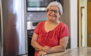 Maria smiles in her kitchen, while leaning on the kitchen counter.